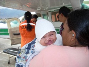 Child with cleft pallet being transported by Mano a Mano for specialist treatment, with support from SAR